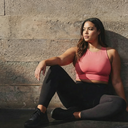 Model wearing ,Cross your Mind in Coral color sitting at gym. Image links to our Instagram. @alexanderjaneboutique