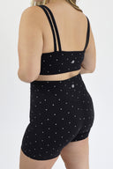 Model wearing Layered Sports Bra with black and white micro polka dot outer layer and solid black under layer.