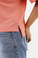 Model wearing Everyday Tee in Coral color. Detail of side seam and drop tail.