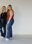 Two women standing side by side wearing blue jeans. Extended image from previous.