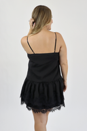 Woman wearing a black lace-trimmed dress against a white background