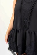 Black dress with lace details on a plain background