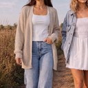 Two women walking outdoors. The woman on the left wears oat knit cardigan over a white cloud tank. Women on right wears smocked v-waist dress and boyfriend denim jacket.