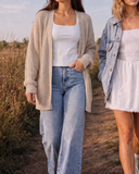 Two women walking outdoors. The woman on the left wears oat knit cardigan over a white cloud tank. Women on right wears smocked v-waist dress and boyfriend denim jacket.